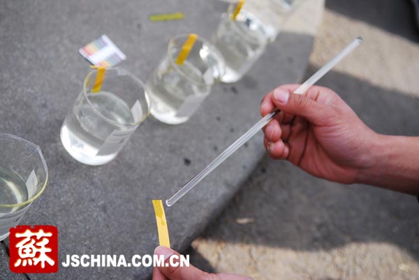 一名同学正在现场用PH试纸测试水体样本酸碱值。