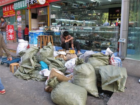 手机回收部分特别吸引人。在大楼外边，可以看到一个小伙子正在整理大袋的手机电路板，估计是在挑拣那些有需